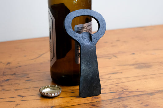 Hand forged steel bottle opener. Rests against beer